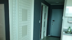 A hallway with white doors, a kitchen area with a sink and a trash can, and a blue wall. - Sajo Resort Gyeongju (Gyeongju)