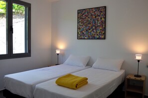 Ein Zimmer mit zwei Betten, einem Fenster, einem Wandbild und zwei Nachttischlampen.