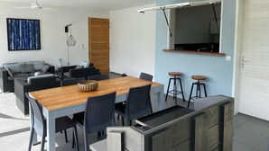Un salon moderne avec une table à manger, des canapés et un téléviseur fixé au mur.