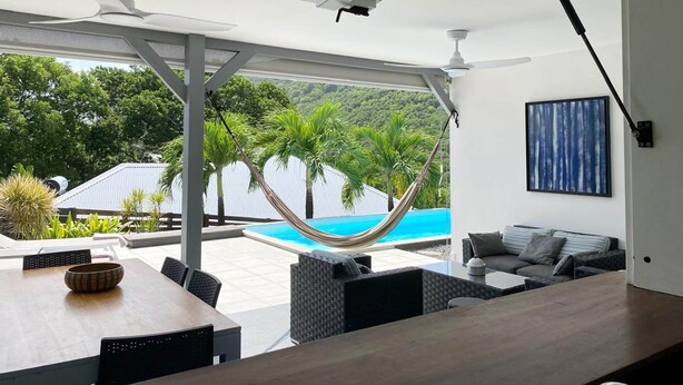 Un espace de vie extérieur moderne, doté d’un hamac, d’une piscine et de coins salon.