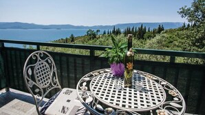 Un balcon avec une table ronde en métal, une chaise et un vase de fleurs.