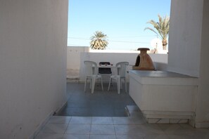 A narrow balcony with a tiled floor, a white table with two chairs, and a terracotta pot. - Sweet home houmt souk Djerba (Djerba)