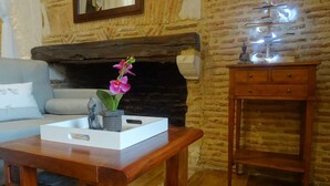 Une pièce chaleureuse avec une cheminée en pierre, une table en bois sur laquelle repose un plateau blanc, une statue de Bouddha et une petite statue de Bouddha sur une étagère.