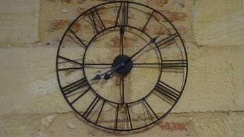 Eine runde Wanduhr mit römischen Ziffern an einer strukturierten Ziegelwand befestigt.