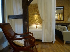 A cozy bedroom with a wooden chair, a bed with white linens, and a stone wall. - Charming Loft "Roxane" - Habitation Saint-Clar - Historic Center - WIFI/Netflix (Bergerac)