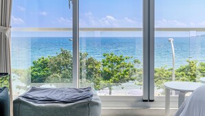 A room with a large window offering a view of the sea and greenery. - Cat at Greece (Hengchun)