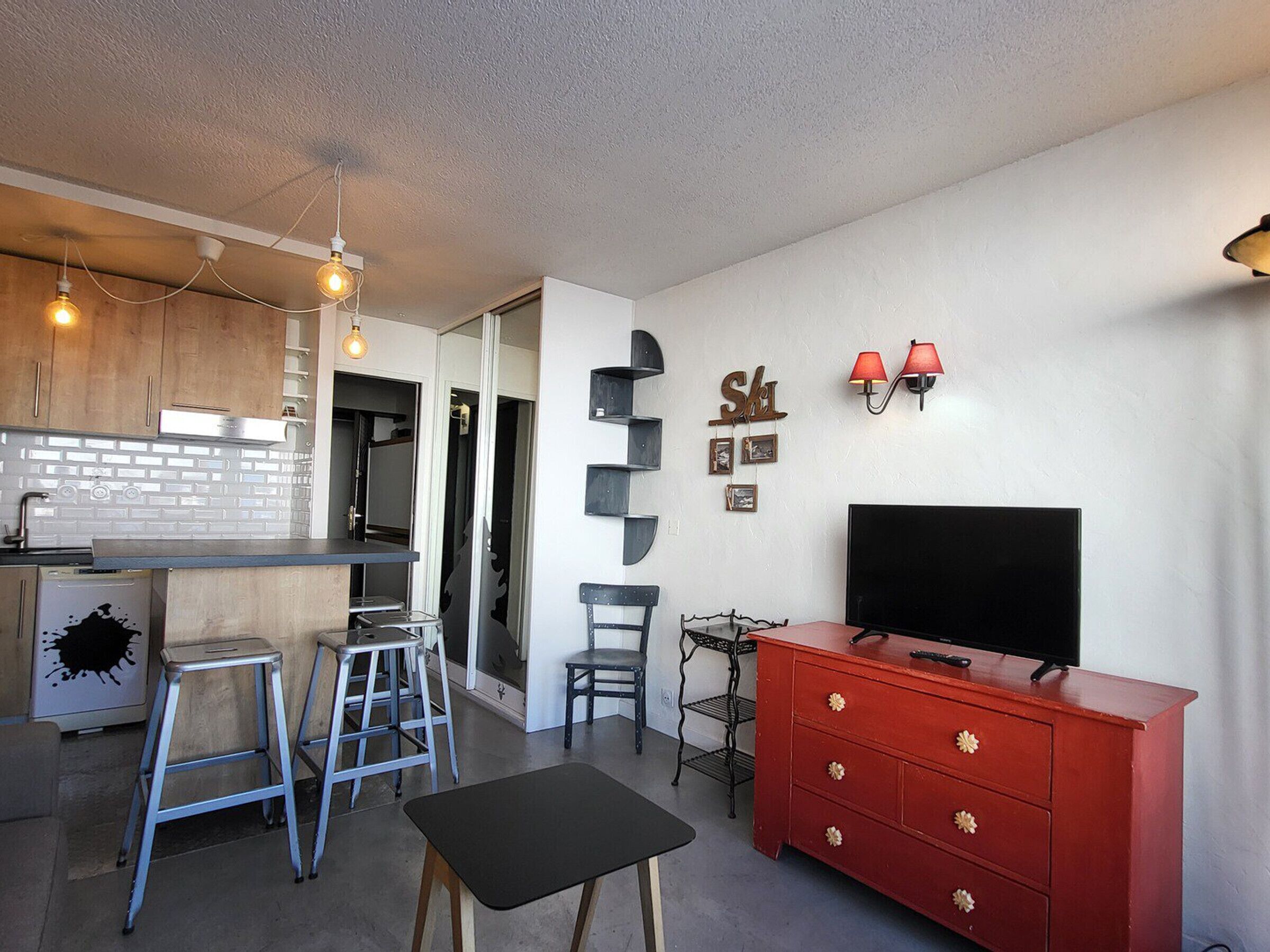 A compact living space with a kitchenette, a dining area, and a TV.