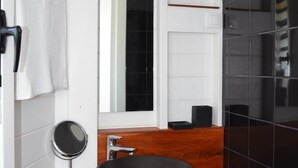 Une salle de bain moderne avec un meuble-lavabo en bois, un grand miroir et un lavabo sur colonne noir.