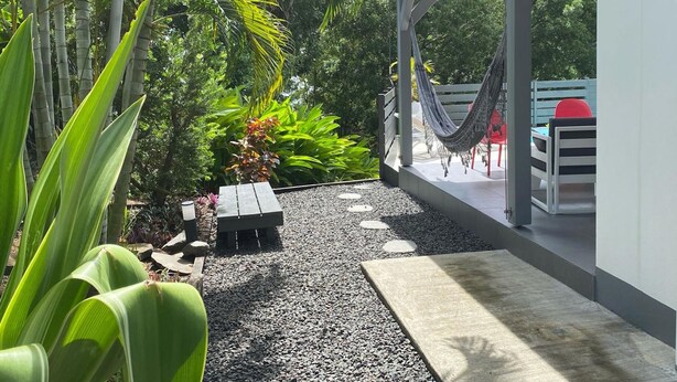 Eine moderne Terrasse im Freien mit einer Hängematte, einer Holzbank und einem kleinen Tisch.