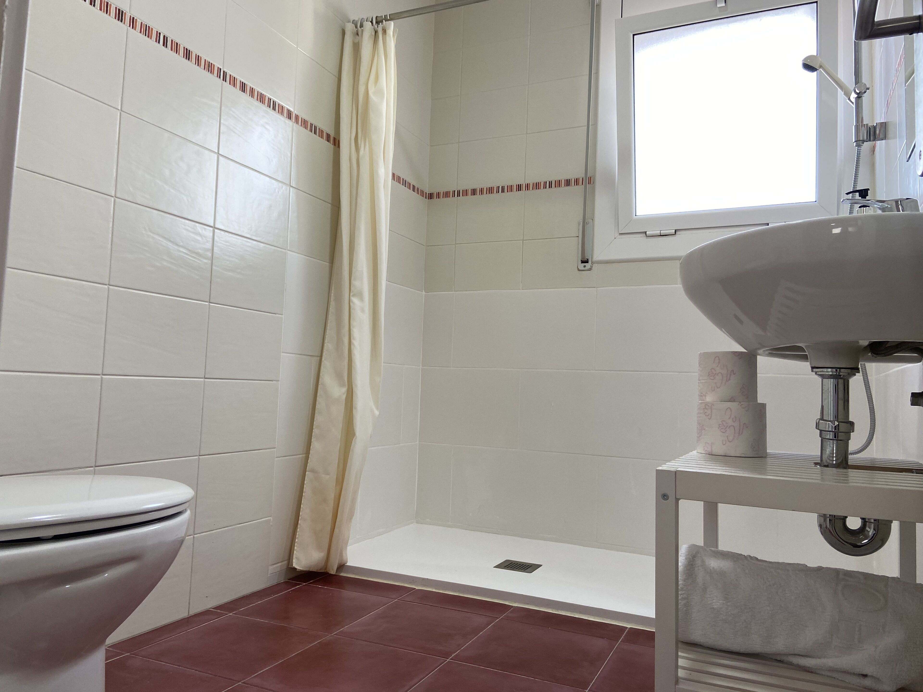 Et badeværelse med toilet, brusebad og vask.