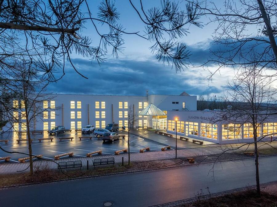 A modern hotel with a large parking area and a prominent glass facade.