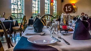 Mesa de jantar posta com configurações numeradas, um vaso e um castiçal.