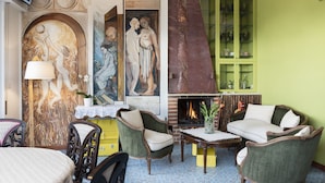 A room with a fireplace, green armchairs, a dining table, and artwork on the walls. - La Foresteria di Maestina (Barcellona Pozzo di Gotto)