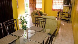 A dining area with a glass table, chairs, and a vase of flowers.