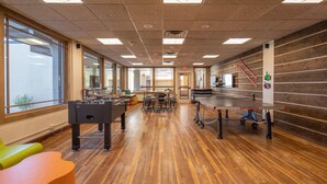 A spacious room with a foosball table, ping pong table, and a foosball table in the center.