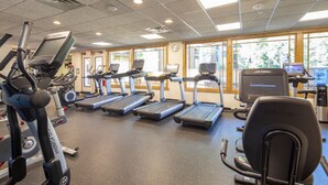 A gym with treadmills, elliptical machines, and a water cooler.
