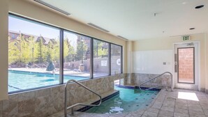 A pool area with clear glass walls, a tiled floor, and an exit door.