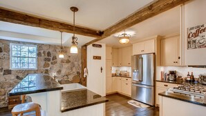 Una cocina moderna con una pared de acento de piedra, vigas de madera, electrodomésticos de acero inoxidable y una zona de bar.