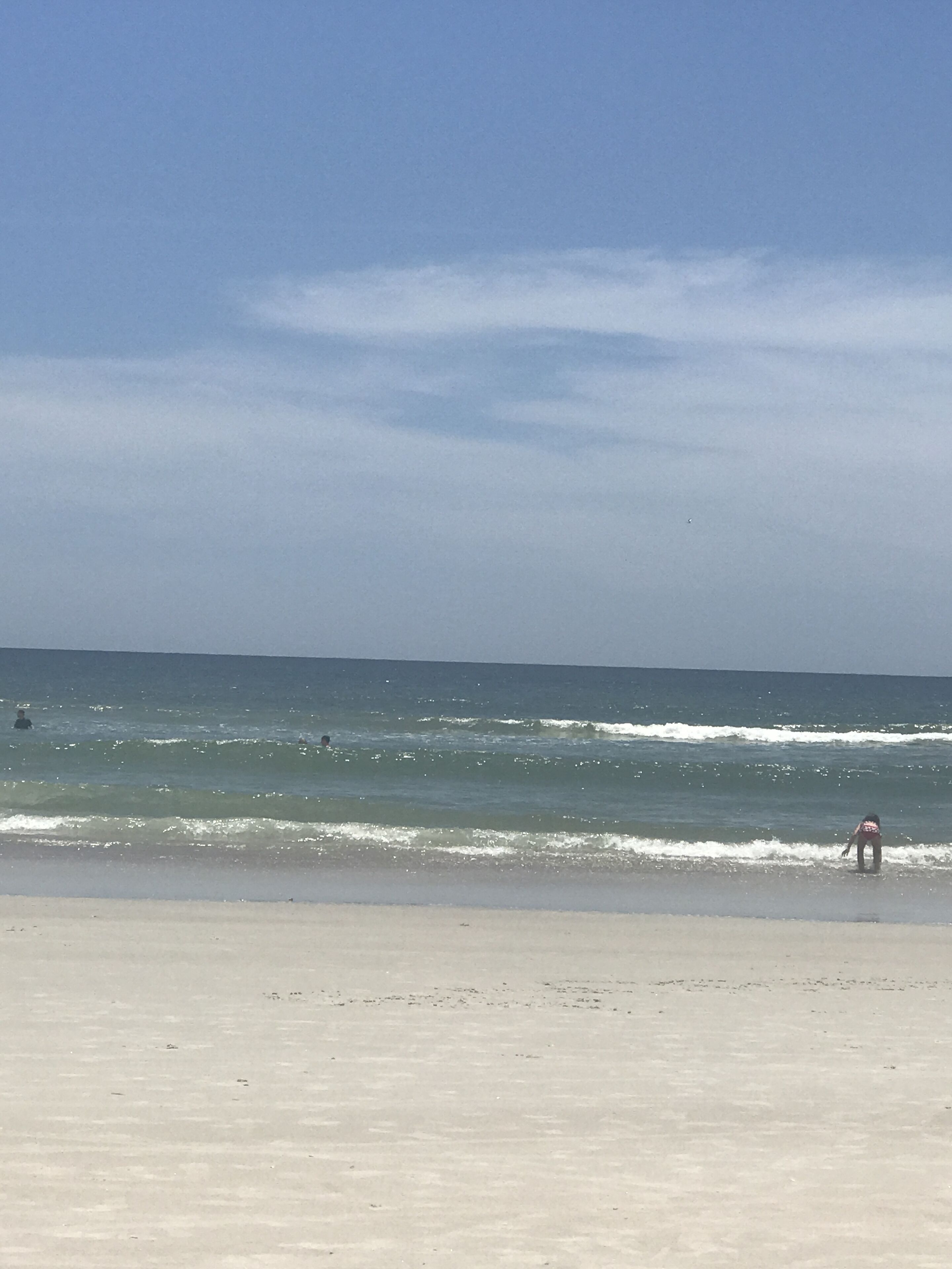 A beach with waves and a clear sky.