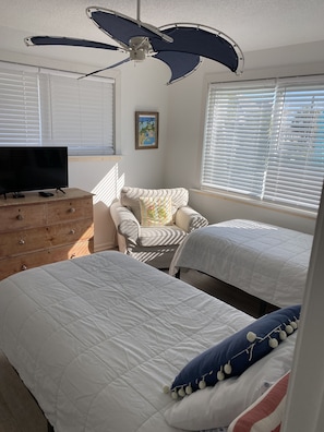 Cozy retreat with two beds, a dresser, and a chair, perfect for a comfortable stay.