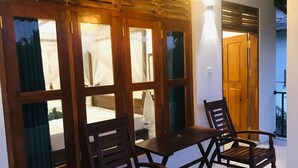 A room with a wooden partition, two wooden chairs, a small table, and a hanging light fixture. - Sea Glow -Tangalle (Tangalle)