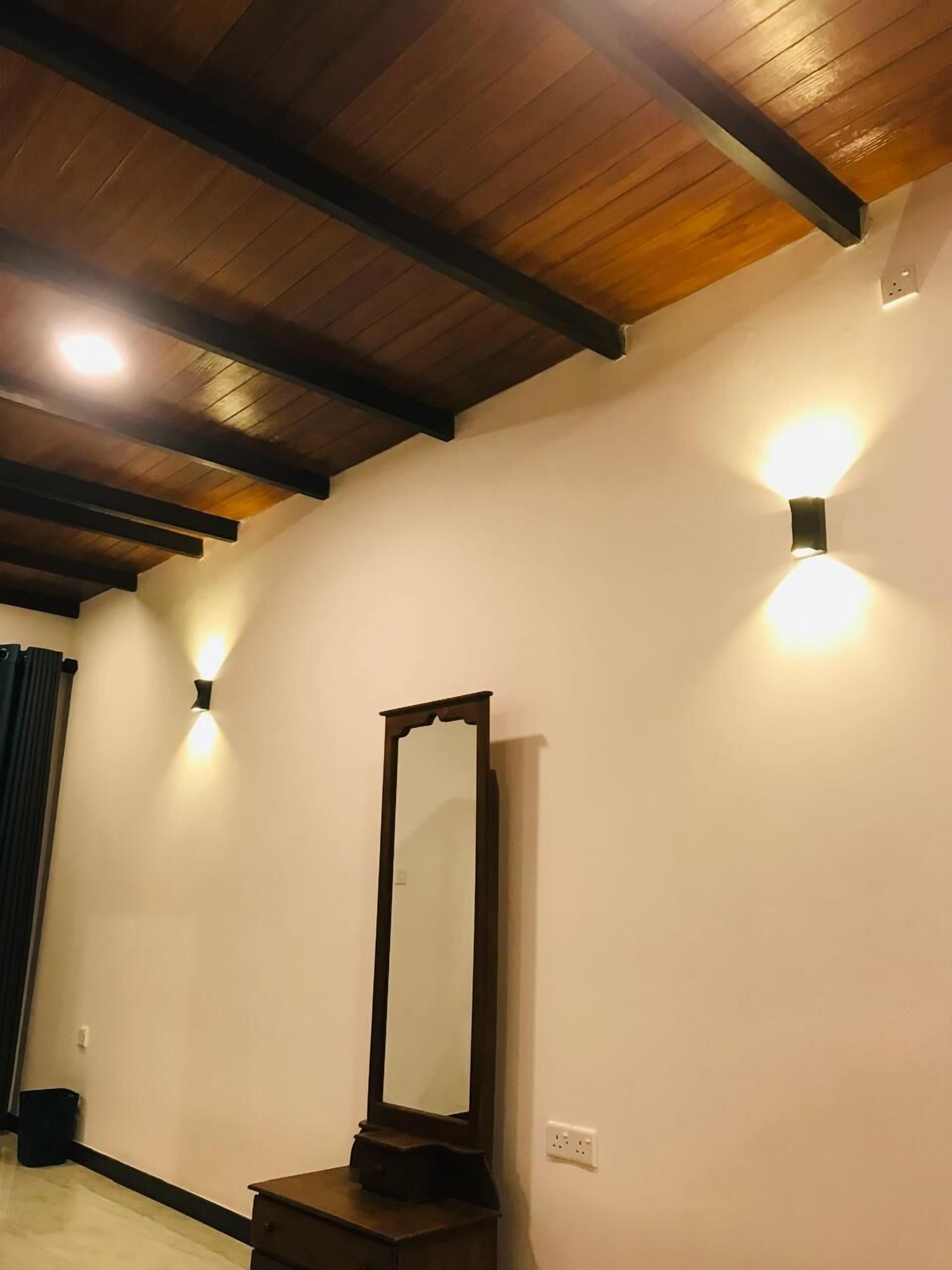 A room with a wooden ceiling, a large mirror, and two wall-mounted lights.