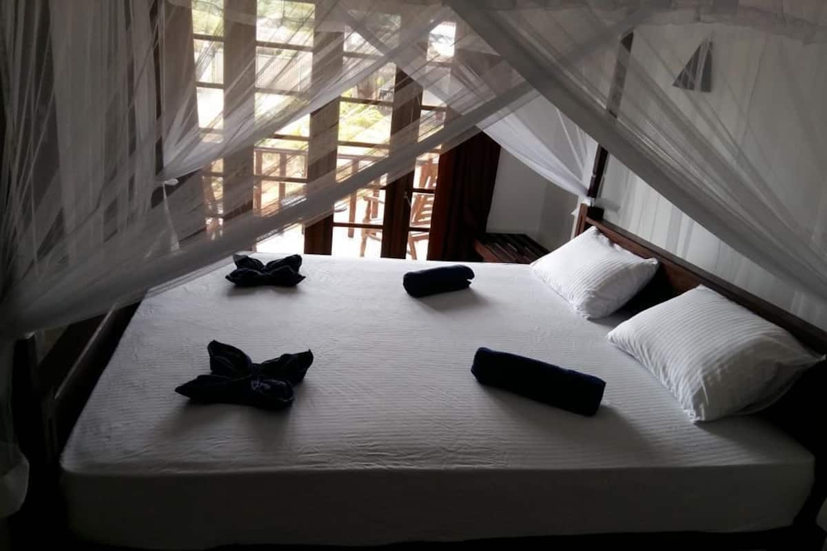 A bed with white linens, a canopy, and pillows.