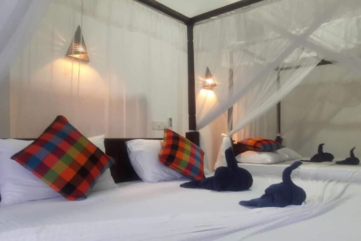A bed with white linens, colorful pillows, and a canopy.