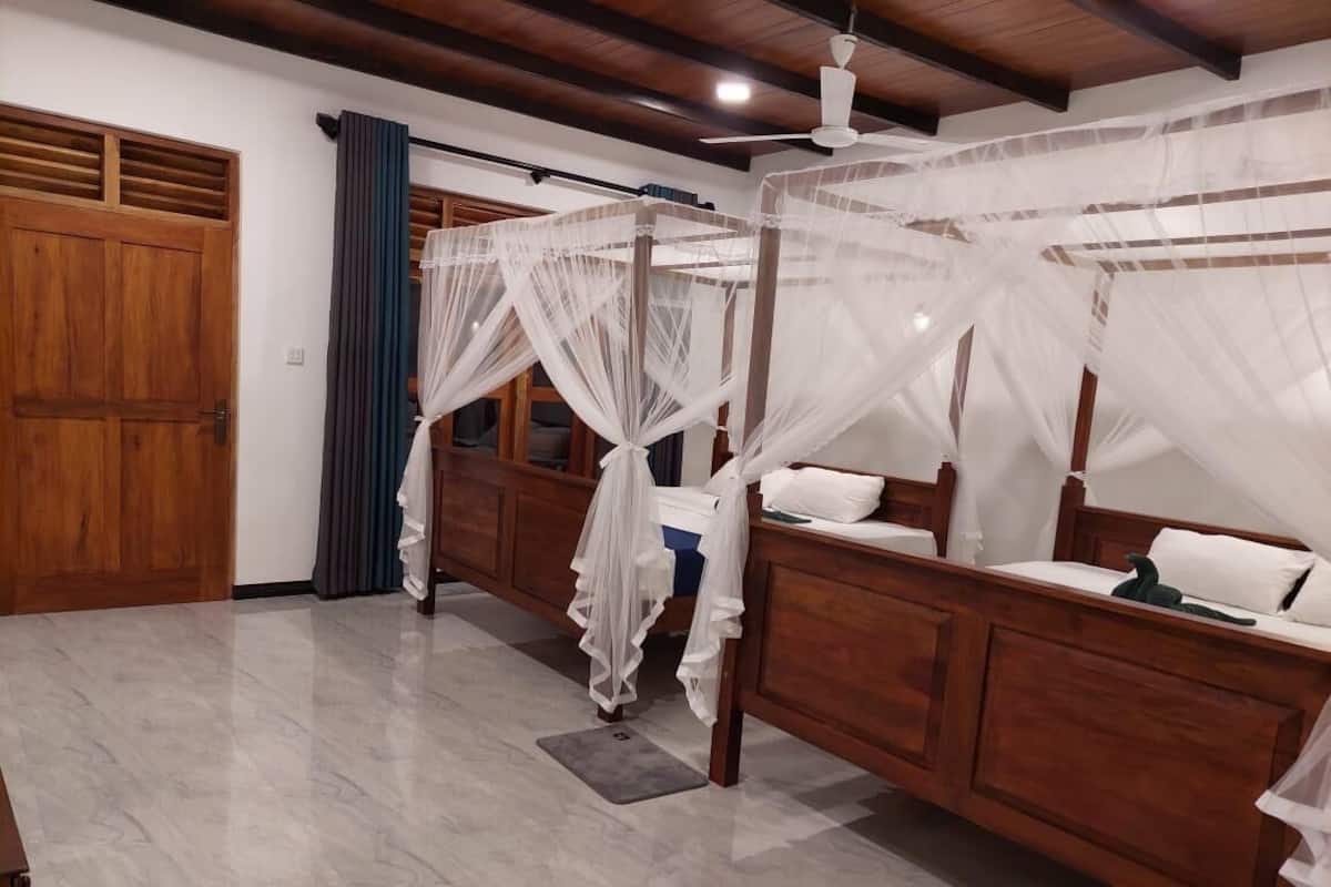 A bedroom with two wooden beds, a large window, and a ceiling fan.