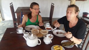 A wooden dining table with white teapots, cups, and plates of food. - Sea Glow -Tangalle (Tangalle)