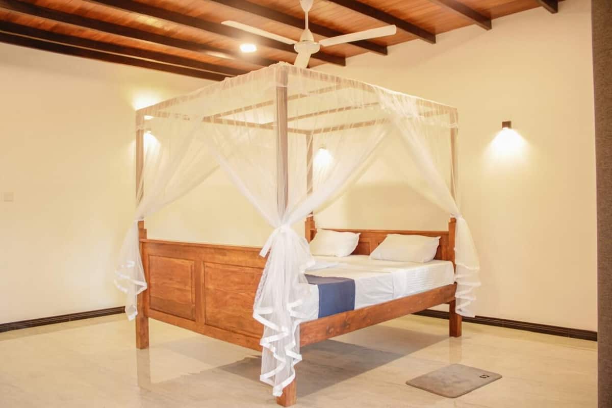 A four-poster canopy bed with white bedding and a wooden frame.