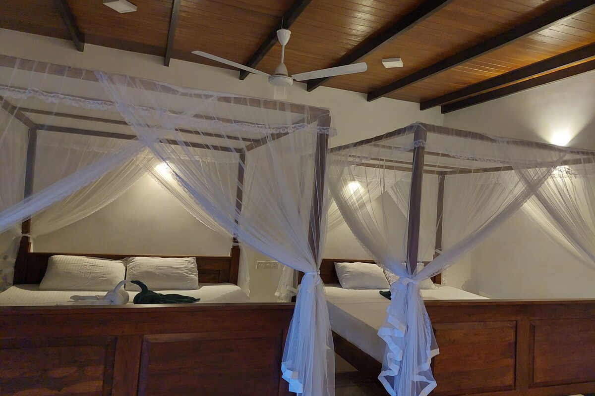 Una habitación con dos camas, cada una con dosel y ventilador de techo.