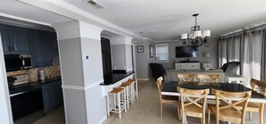 Une cuisine moderne avec des meubles de couleur sombre, un plan de travail noir et un coin bar avec des tabourets blancs.
