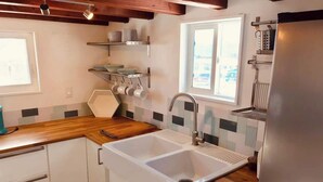 Een praktische keuken met een dubbele spoelbak, houten aanrechtblad, witte kastjes en een raam voor natuurlijk licht.