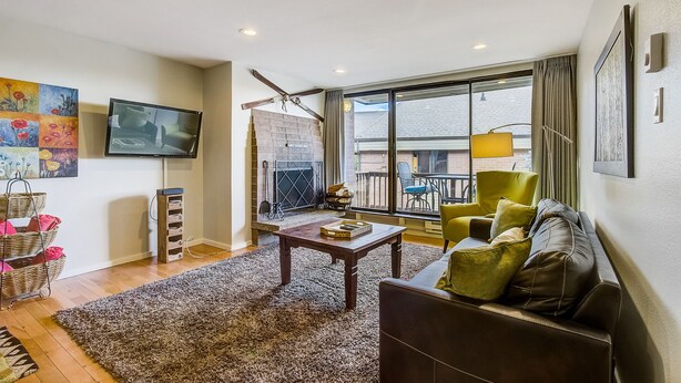 A living room with a fireplace, a television, a sofa, and a large window.