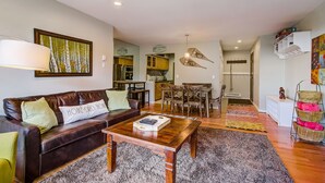 A modern living room with a brown leather sofa, a wooden coffee table, and a large painting on the wall.