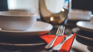 A dining table with a white bowl, a red napkin, and silverware. - Evergreen Apartments (Northampton)