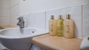 A bathroom with a sink and three bottles of lotion on the countertop. - Evergreen Apartments (Northampton)