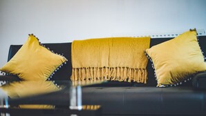 A black sofa with two yellow pillows and a yellow throw blanket with tassels. - Evergreen Apartments (Northampton)