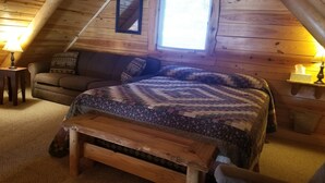 Un dormitori d'àtic acollidor amb un llit de fusta, un sofà i una taula petita.