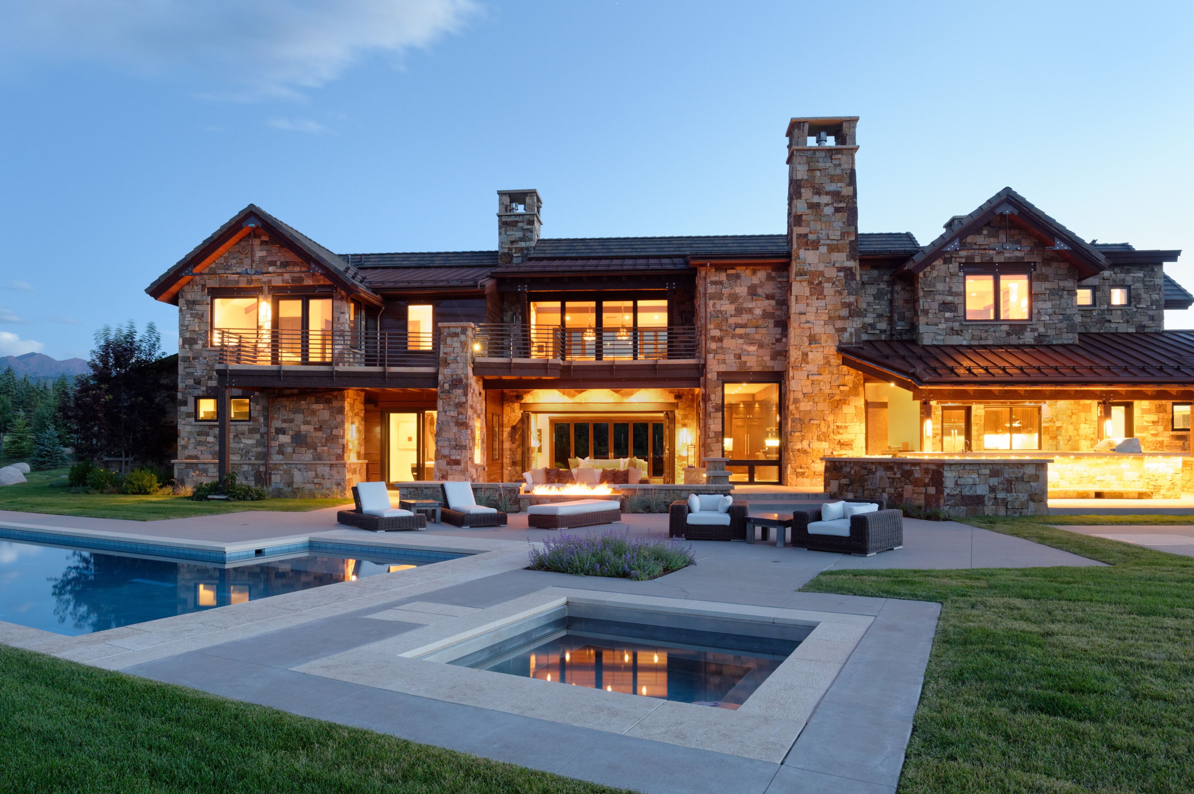 Una gran casa de piedra con piscina, mobiliario de exterior y chimenea.