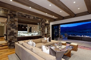 Un salon moderne avec un mur d’accent en pierre, un grand canapé et un coin repas offrant une vue sur les montagnes.