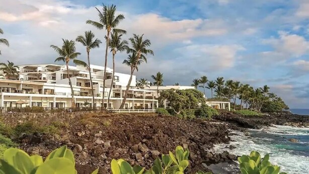 A coastal hotel with multiple white buildings, palm trees, and a rocky shoreline. - Ocean Front Condo at The Royal Sea-Cliff Resort (Kailua Kona)