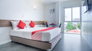 A hotel room with a large bed, a TV mounted on the wall, and a view of the city through the window. - 18 Suites Cebu (Cebu City)