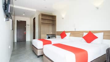 A hotel room with two beds, a wardrobe, and a TV mounted on the wall.