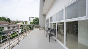 A balcony with a metal railing, two black chairs, and a bicycle in the background. - 18 Suites Cebu (Cebu City)