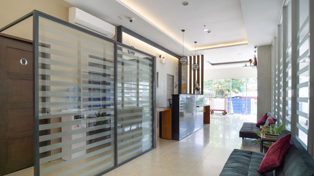 A modern interior with a sliding glass partition, a reception desk, a sofa, and a view of the outdoors. - 18 Suites Cebu (Cebu City)