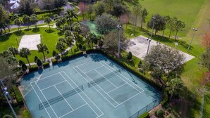 An aerial view of a tennis court surrounded by trees and grass.