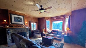 A cozy living room with a fireplace, leather sofa, and a ceiling fan.