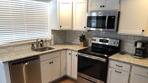 A modern kitchen with white cabinets, stainless steel appliances, and a granite countertop.